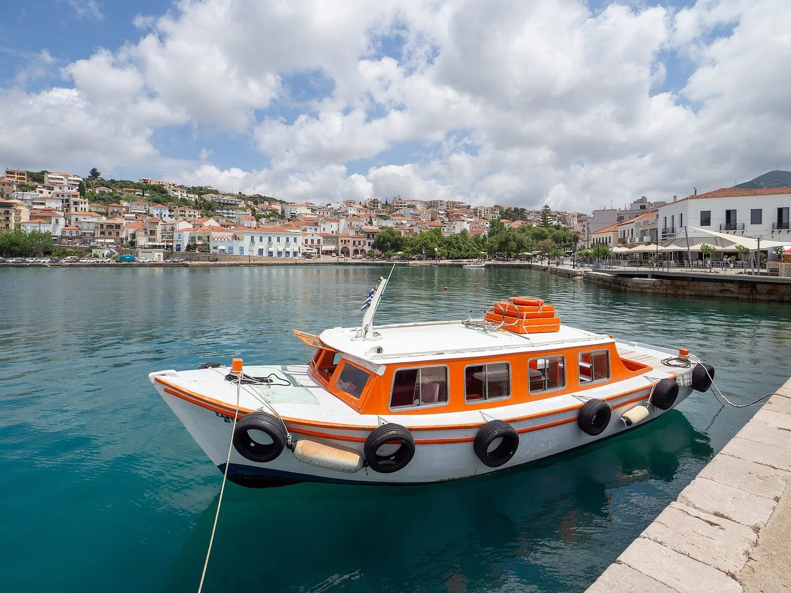 Il porto di Pylos con una barca ormeggiata e le case affacciate sulla baia
